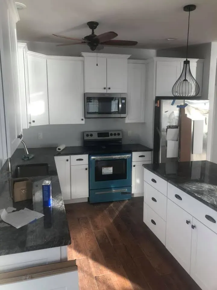Finished kitchen with white cabinets, dark granite and wood floors