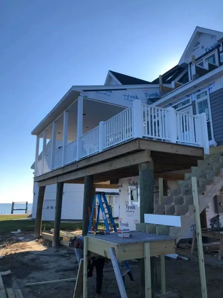 Raised coastal home with wraparound deck under construction