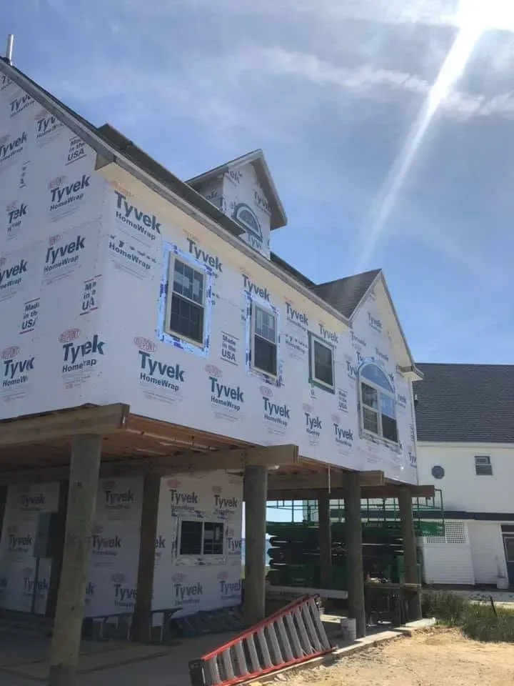 Raised home in house wrap standing on pilings